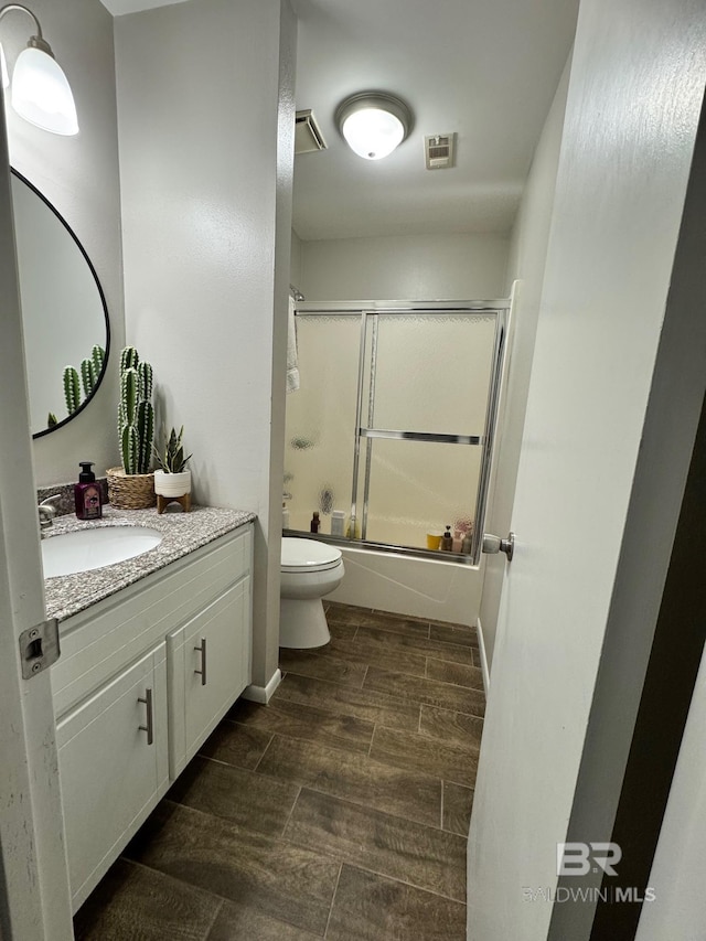 full bathroom with vanity, enclosed tub / shower combo, and toilet