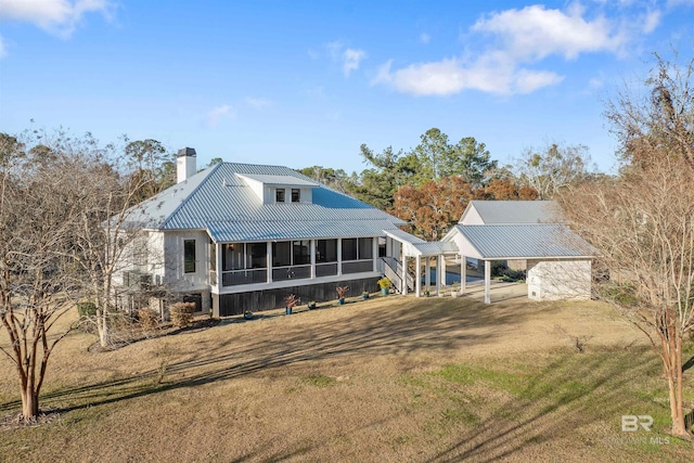 rear view of house with a lawn, a sunroom, and a carport