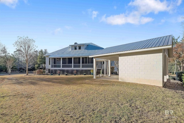 rear view of house featuring a carport, a sunroom, and a lawn