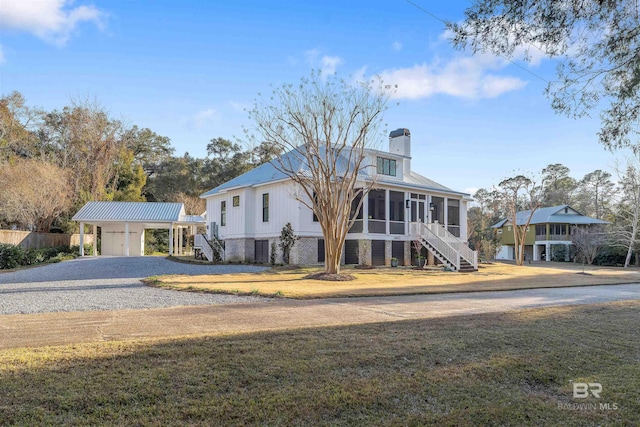 view of front of house featuring a front yard, a sunroom, and a carport