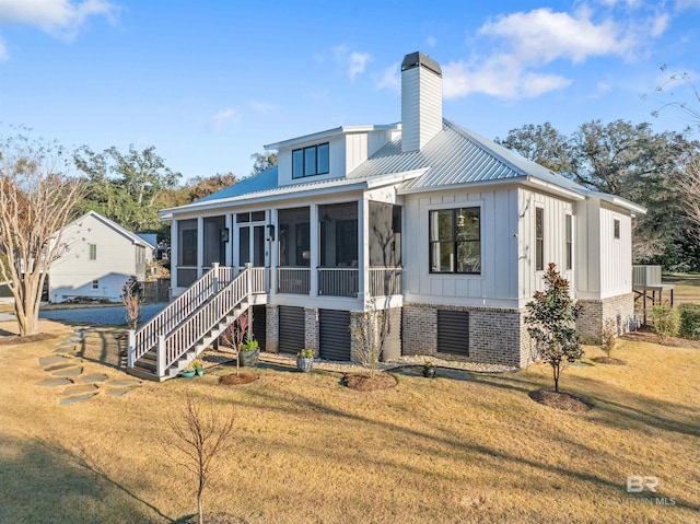 rear view of house featuring a sunroom and a lawn