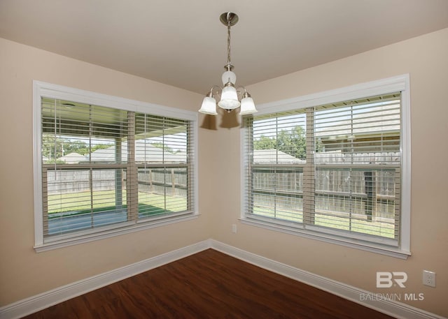 unfurnished room with a notable chandelier, plenty of natural light, and wood-type flooring