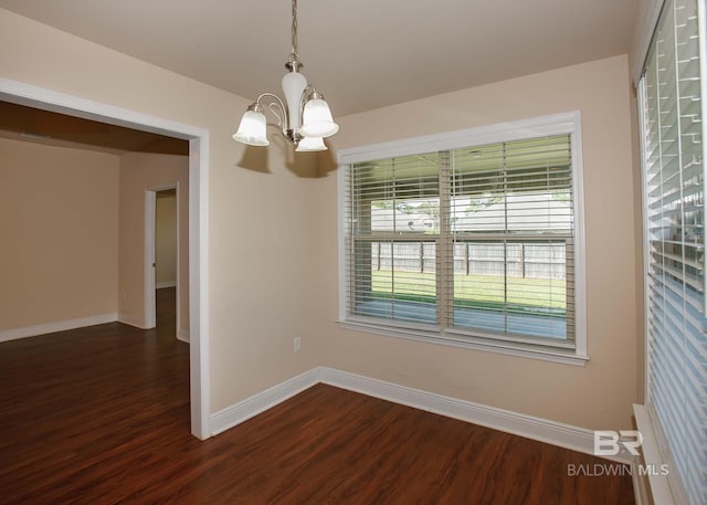 empty room featuring dark hardwood / wood-style flooring and a notable chandelier