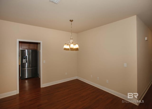 empty room featuring dark hardwood / wood-style floors and an inviting chandelier