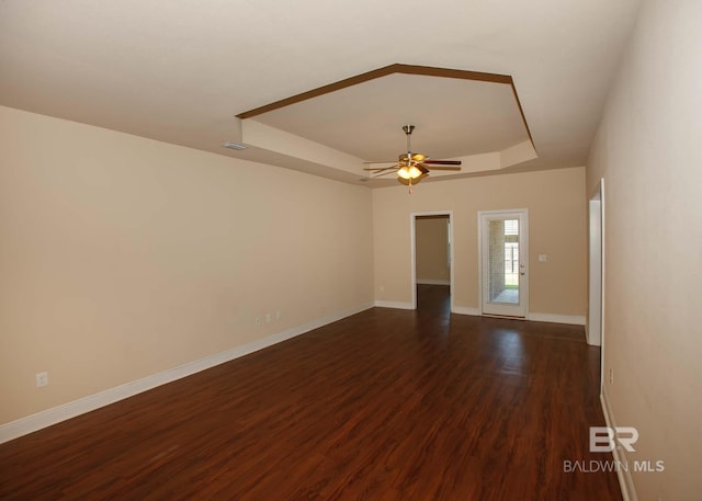 spare room featuring ceiling fan, a raised ceiling, and dark hardwood / wood-style floors