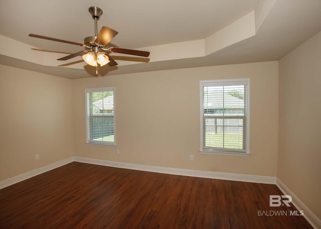 spare room with a wealth of natural light, a tray ceiling, ceiling fan, and hardwood / wood-style flooring