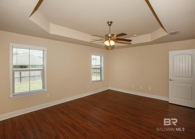 unfurnished room with ceiling fan, a raised ceiling, and dark hardwood / wood-style floors