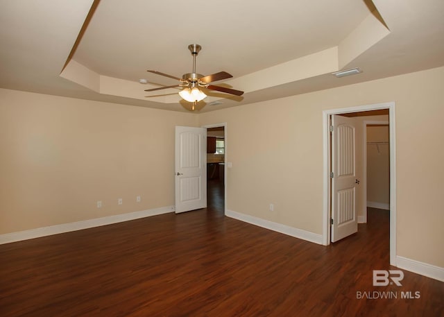 unfurnished room with dark hardwood / wood-style flooring, a tray ceiling, and ceiling fan