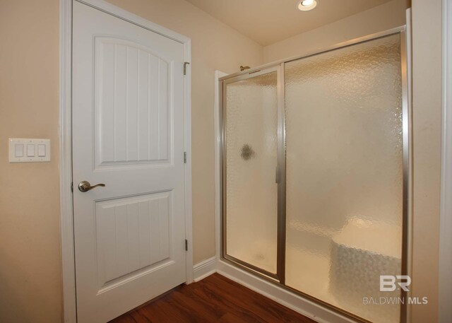 bathroom featuring an enclosed shower and hardwood / wood-style flooring