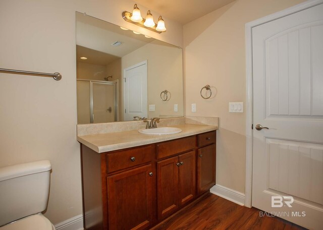 bathroom with an enclosed shower, toilet, hardwood / wood-style flooring, and vanity