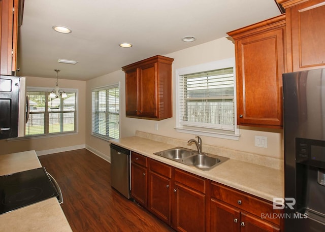 kitchen featuring dark hardwood / wood-style flooring, hanging light fixtures, appliances with stainless steel finishes, sink, and an inviting chandelier