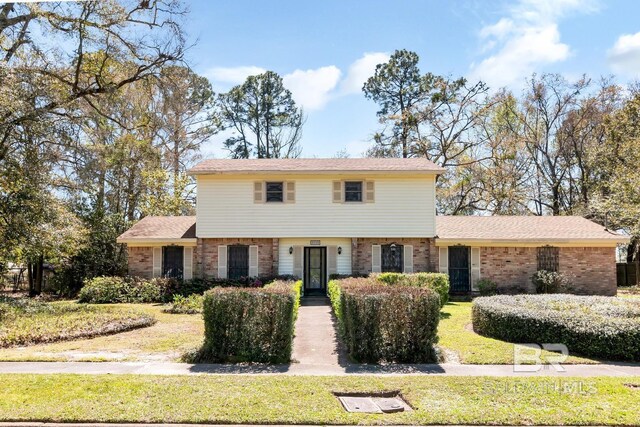 colonial home featuring brick siding and a front lawn