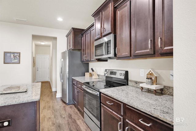 kitchen with visible vents, dark brown cabinetry, light stone countertops, light wood-style floors, and appliances with stainless steel finishes