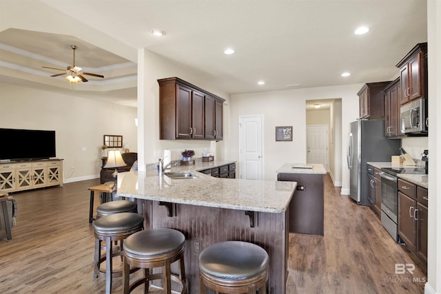 kitchen featuring a center island, stainless steel appliances, baseboards, open floor plan, and wood finished floors