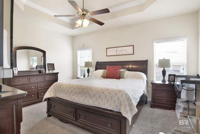 bedroom featuring a ceiling fan, ornamental molding, light carpet, and a tray ceiling