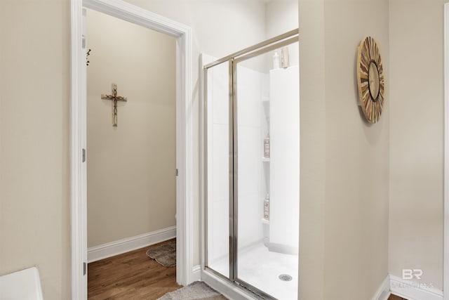 full bath featuring baseboards, wood finished floors, and a shower stall