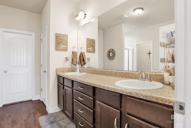bathroom featuring double vanity, a sink, baseboards, and wood finished floors