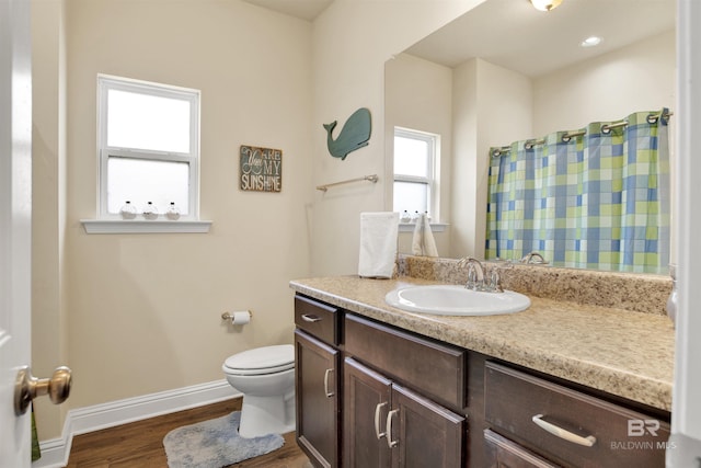 bathroom featuring a shower with curtain, wood finished floors, baseboards, vanity, and toilet