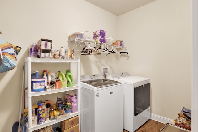 laundry area featuring laundry area, baseboards, washing machine and dryer, and wood finished floors