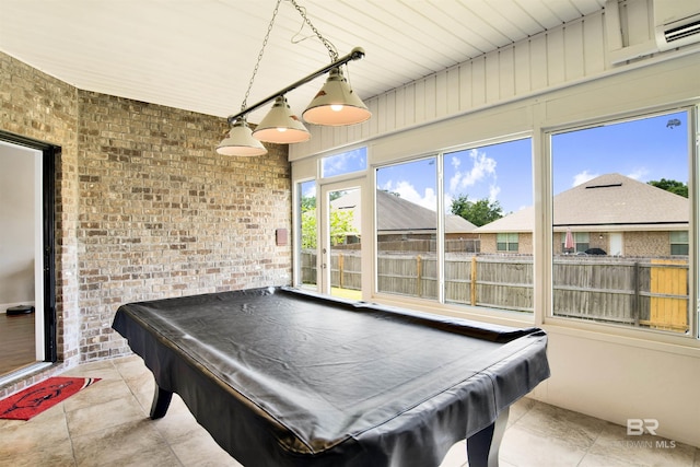 playroom featuring pool table, a wall unit AC, tile patterned flooring, and brick wall