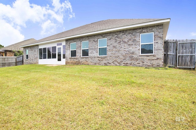 back of property with fence, a yard, and brick siding