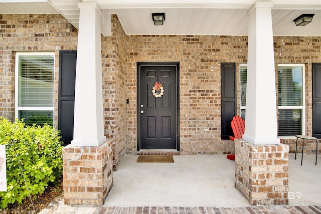doorway to property with covered porch and brick siding