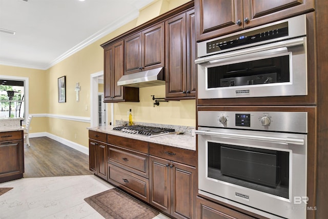 5698 Spring Landing Dr, Theodore, AL 36582 - kitchen with under cabinet range hood, appliances with stainless steel finishes, crown molding, light stone countertops, and dark brown cabinets