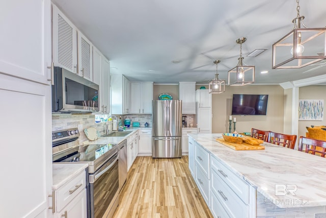 684 Chickasaw Rd, Gulf Shores, AL 36542 - kitchen featuring stainless steel appliances, white cabinets, light wood-style floors, decorative backsplash, and pendant lighting