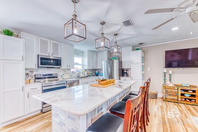684 Chickasaw Rd, Gulf Shores, AL 36542 - kitchen with stainless steel appliances, a kitchen island, ceiling fan, light wood-type flooring, and tasteful backsplash