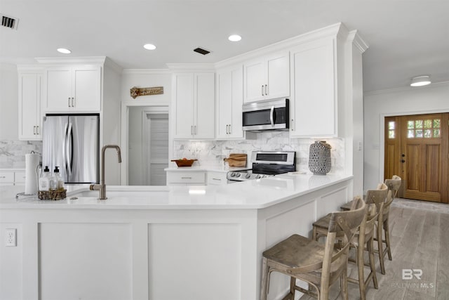 kitchen featuring decorative backsplash, white cabinets, and stainless steel appliances