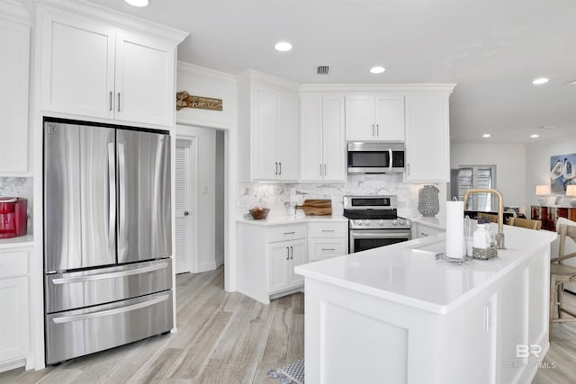 kitchen featuring light countertops, decorative backsplash, stainless steel appliances, and white cabinetry