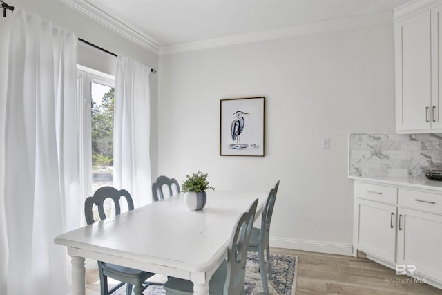 dining room featuring baseboards, ornamental molding, and light wood finished floors