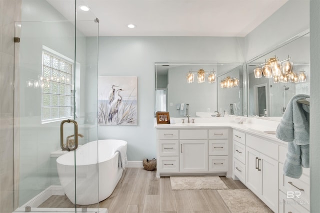 full bath featuring a sink, double vanity, a shower stall, wood finished floors, and a soaking tub