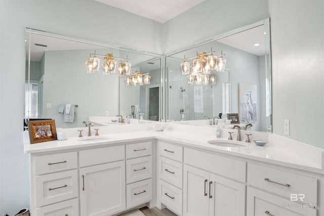 full bathroom featuring double vanity, a sink, walk in shower, and a chandelier