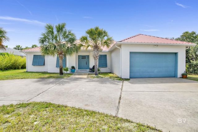 single story home featuring a garage, a front lawn, stucco siding, metal roof, and driveway