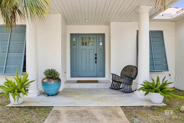doorway to property with brick siding and covered porch