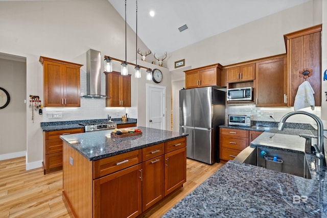1609 Makaira Dr, Foley, AL 36535 - kitchen featuring appliances with stainless steel finishes, wall chimney range hood, high vaulted ceiling, a kitchen island, and dark stone countertops