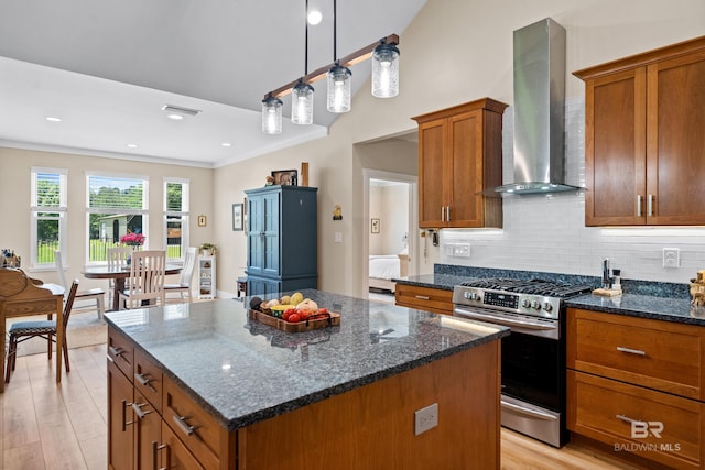 1609 Makaira Dr, Foley, AL 36535 - kitchen featuring stainless steel gas stove, wall chimney range hood, a kitchen island, light wood-style floors, and brown cabinets