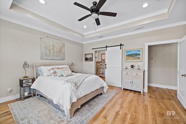 1609 Makaira Dr, Foley, AL 36535 - bedroom featuring a tray ceiling, a barn door, recessed lighting, light wood-style flooring, and ornamental molding
