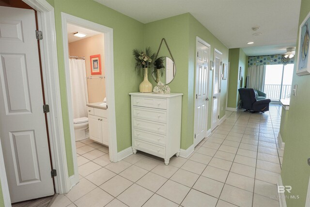 corridor with light tile patterned floors and baseboards