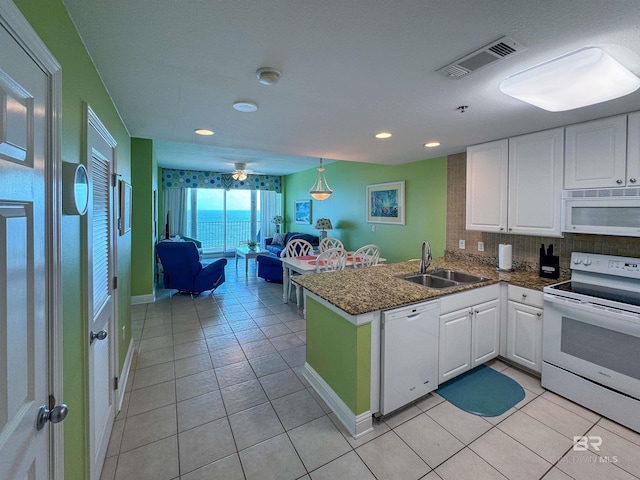 kitchen with a peninsula, white appliances, a sink, visible vents, and white cabinets