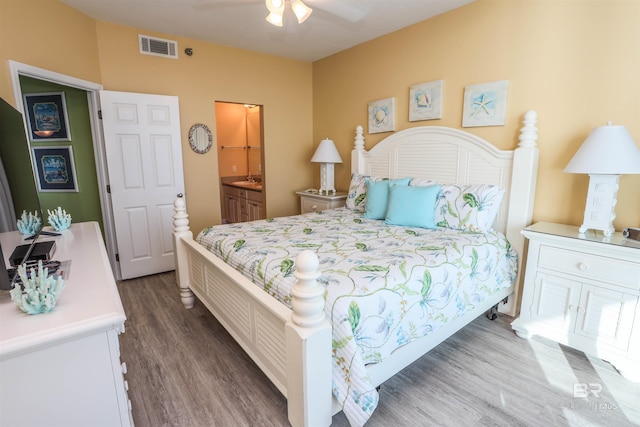 bedroom with ceiling fan, visible vents, dark wood-type flooring, and ensuite bathroom