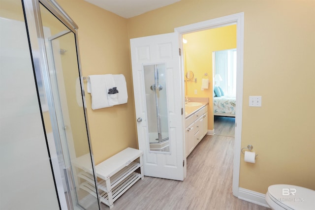 bathroom featuring ensuite bathroom, toilet, wood finished floors, baseboards, and a stall shower