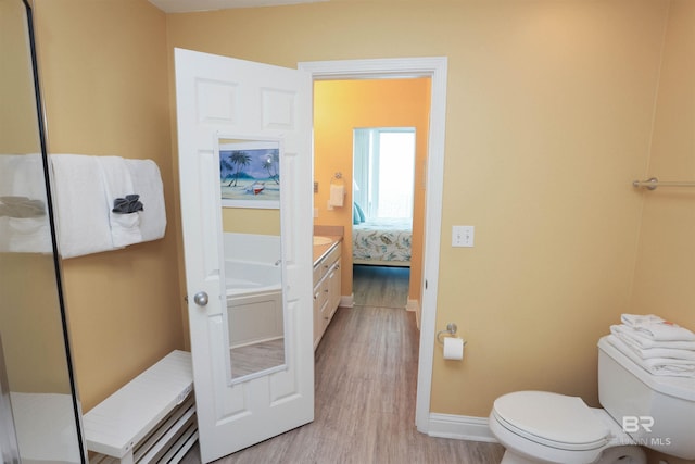 full bath featuring baseboards, toilet, wood finished floors, ensuite bathroom, and vanity