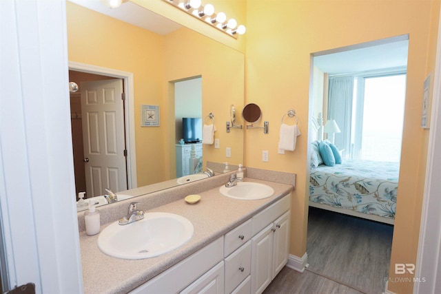 full bath featuring double vanity, wood finished floors, ensuite bath, and a sink