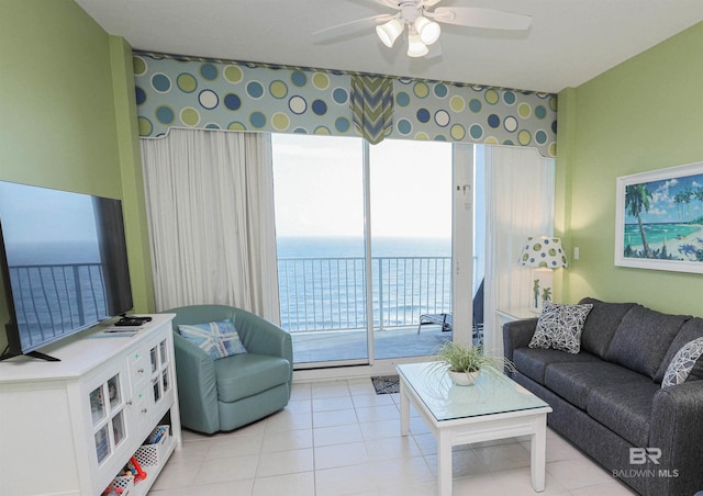 living area with light tile patterned floors, a water view, and a ceiling fan