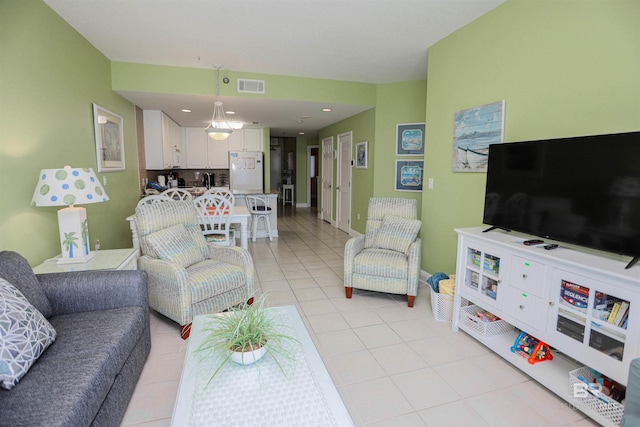 living area with light tile patterned floors, visible vents, and baseboards