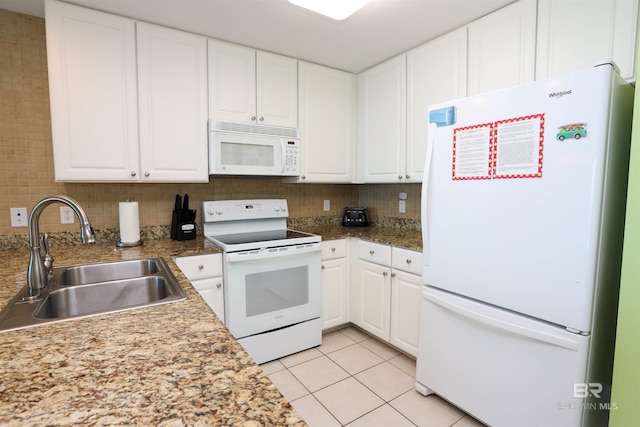 kitchen featuring white appliances, light tile patterned floors, white cabinets, and a sink