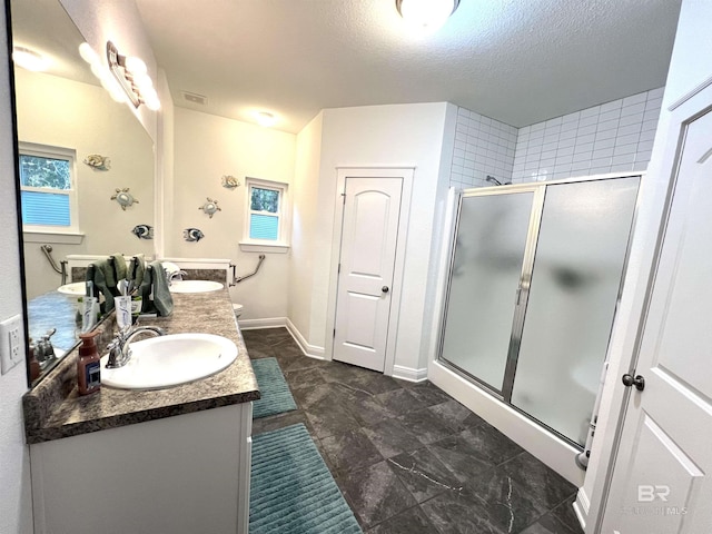 bathroom with a textured ceiling, vanity, and an enclosed shower