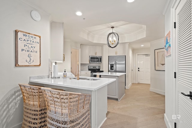 kitchen featuring appliances with stainless steel finishes, white cabinetry, pendant lighting, kitchen peninsula, and a raised ceiling